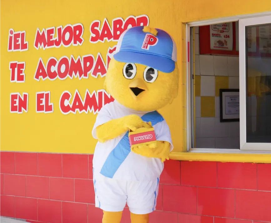 Mascota de Pinulito frente a una sucursal, con el Micha Micha